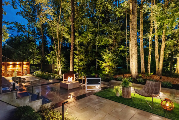a patio with a fire pit and chairs in the middle of trees