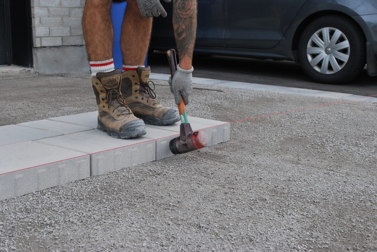 Homme posant des pavés sur gravier.