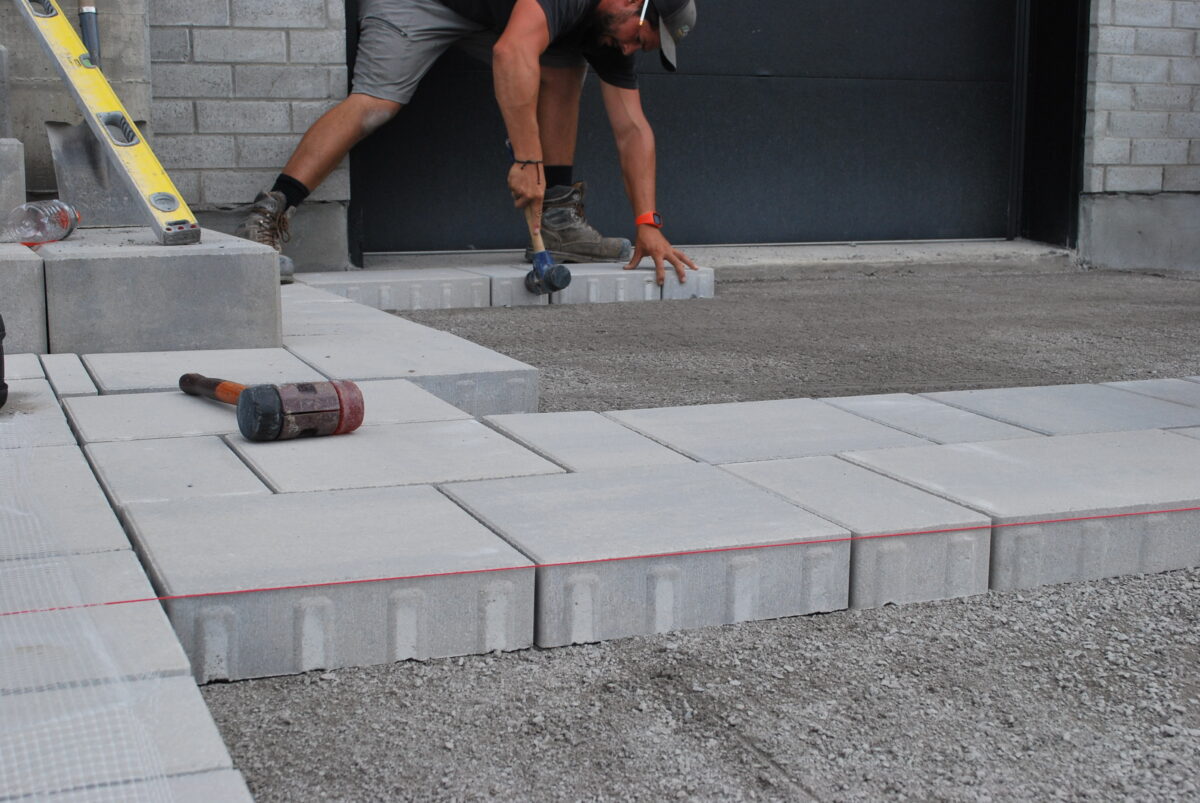 Homme posant des pavés en béton.